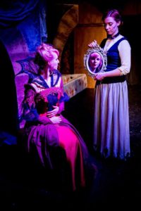 Kate (Aiyanna Wade) holds the mirror for Elizabeth (Mary-Kate Arnold). Kate's makeup design by Jay Megan Sushka. Lighting by Benjamin Dionysus. Costumes by Delena Bradley. Photo by iNDie Grant Productions.